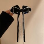 hand holding large bow hair clip with rhinestone and long ribbon
